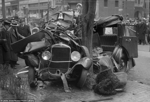 Officers examine a car that has wrapped itself around a tree, spilling its interiors onto the street in Boston in 1933