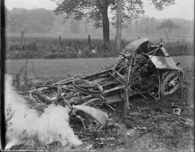 Children peer out of the undergrowth as photographer Leslie Jones captures a nasty wreck smouldering by the side of the road in Hingham