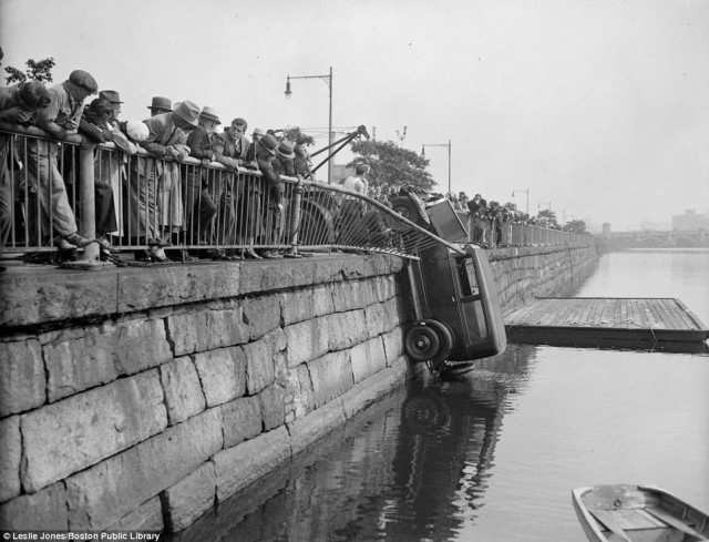 Crowds watch in awe as a car is winched out of the Charles River in Cambridge, Mass in 1933. close to the Harvard University campus