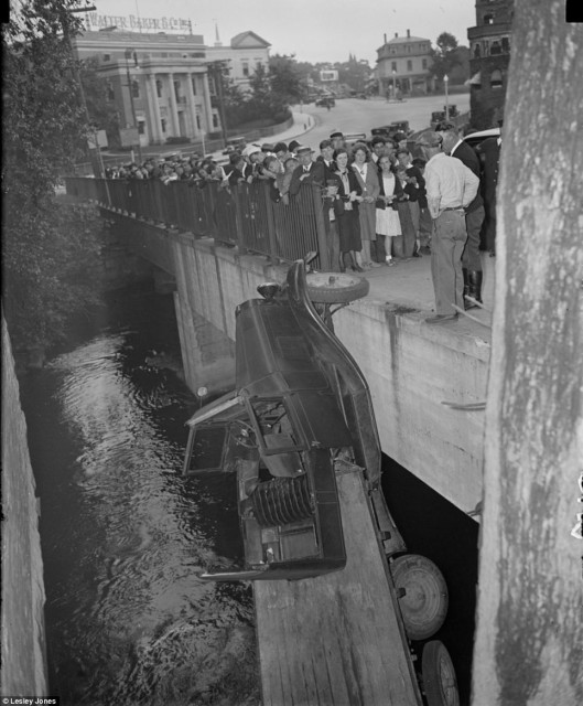 Taken in 1934, this photograph shows a truck balancing on a bridge in Dorchester by just one wheel. Workers from the Walter Baker &amp; Co chocolate factory rushed out of the building in the background to watch